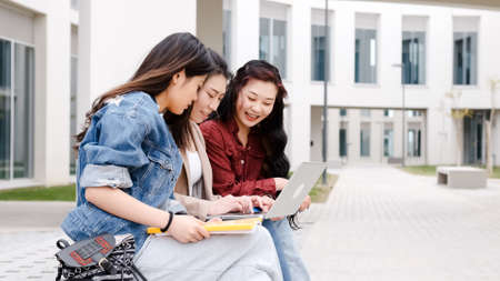 three asian girl students using the laptop at break time sitting on campusの写真素材