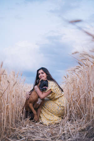 Portrait of a young woman hugging her dog in the middle of a wheat field. Nature and animals conceptの写真素材