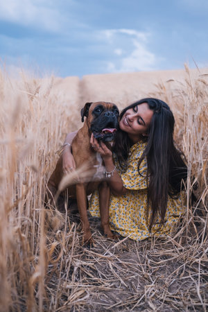 Portrait of a young woman hugging her dog in the middle of a wheat field. Nature and animals conceptの写真素材