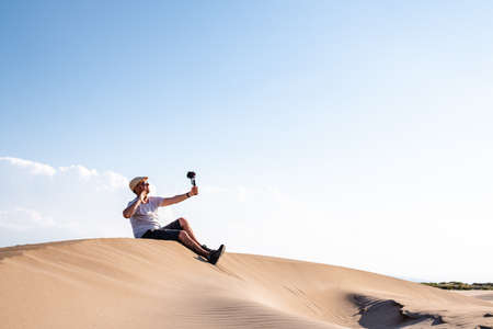 Man sitting and taking selfies on sand duneの写真素材