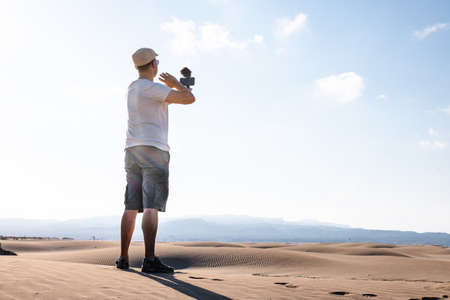 Man filming himself with his cell phone in the desert dunes. Traveling male content creatorの写真素材
