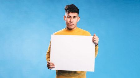 Man looking at camera while holding blank white sign over an isolated background.の写真素材