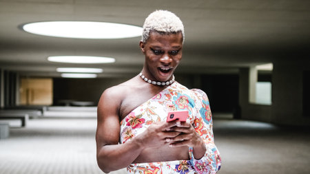 Androgynous black person using cellphone in modern interiorの写真素材