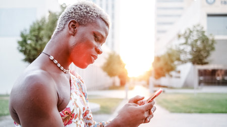 Black androgynous man using smartphone on streetの写真素材