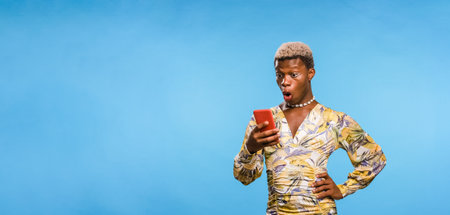 African androgynous person texting on cellphone on blue backgroundの写真素材