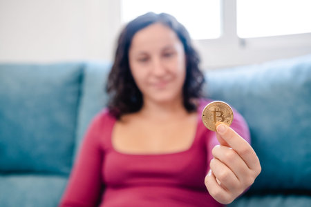 Unfocussed young woman with a bitcoin coin in her hand at home