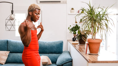 Transgender black dancer in red dress dancing in front of cellphone while record for social mediaの写真素材