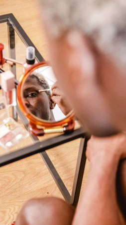 African American non binary person looking in mirror during makeup applicationの写真素材