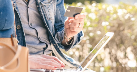Crop woman typing on laptop while man holding credit cardの写真素材