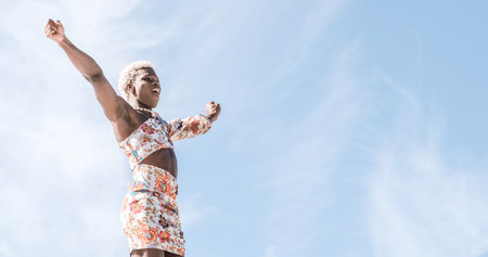 Happy black non-binary person dancing on street and enjoying freedomの写真素材