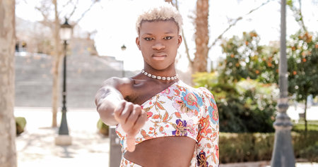Transgender person looking angry and upset while standing outdoors with arms crossed.の写真素材
