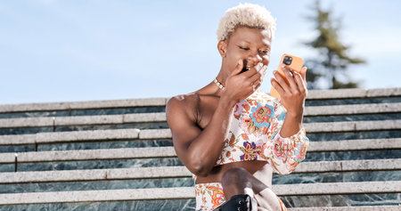 Focused black transgender person applying mascara on streetの写真素材