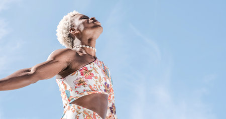 Happy black non-binary person dancing on street and enjoying freedomの写真素材