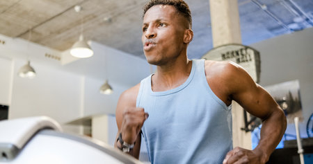 Strong young black sportsman running on treadmill during cardio trainingの写真素材
