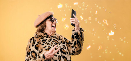 Cheerful aged woman in fashion clothes using smartphone and take a selfieの写真素材