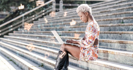 Black transgender person using laptop on stairsの写真素材