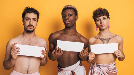 Trans people covering their breasts with white sign with serious look on yellow backgroundの写真素材