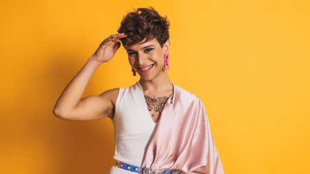 Transgender man with pink clothes and make up smiling at the camera on yellowの写真素材