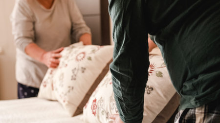 Gay couple finishing making bed together in the morning