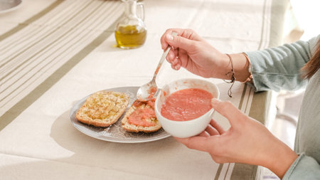 Unrecognizable person spreading tomato on the bread sitting on a tableの写真素材