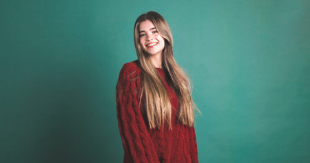 Happy woman with long blonde hair smiling in green studio