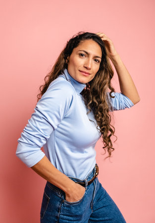 Smiling stylish Colombian woman with curly long hair in studioの写真素材