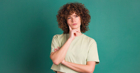 Thoughtful woman touching face on green backgroundの写真素材