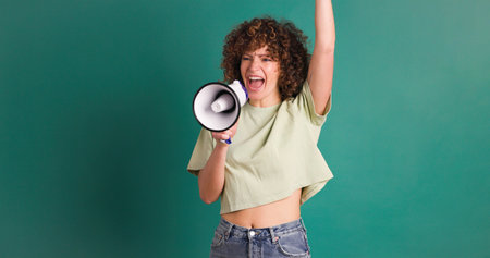 Excited woman screaming on loudspeaker in green studioの写真素材