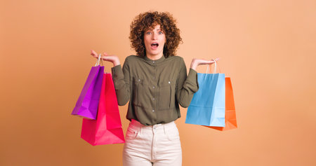 Happy woman with shopping paper bags in beige studioの写真素材