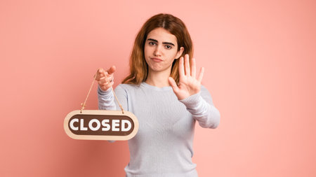 Angry woman showing closed sign and palm in pink studioの写真素材