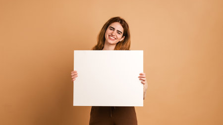 Happy woman holding blank placard in beige studioの写真素材