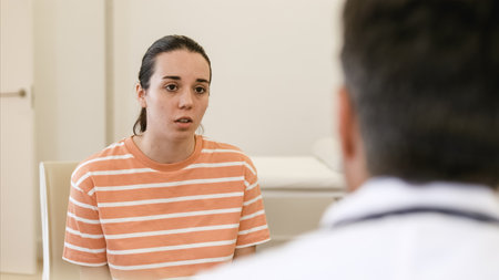 Young sick woman talking with doctor at clinicの写真素材