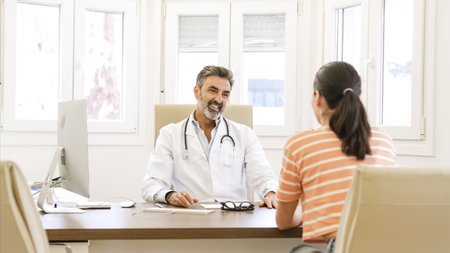 Happy male doctor talking to female patient in clinicの写真素材