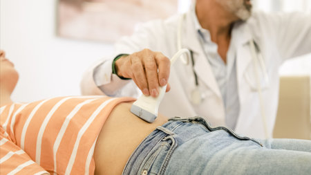 Doctor doing abdomen ultrasound examination of woman in hospitalの写真素材