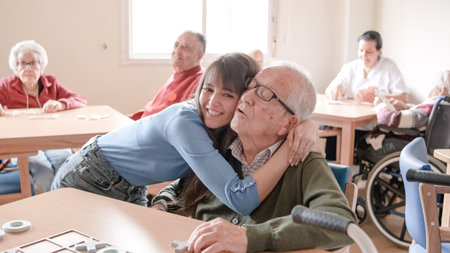Happy young woman embracing grandfather in nursing homeの写真素材