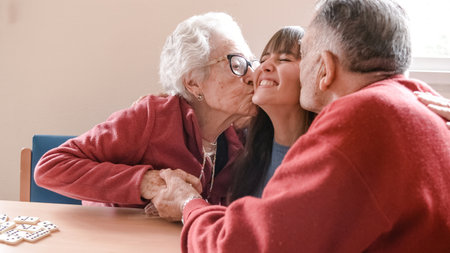 Happy grandparents hugging and kissing granddaughter in nursing homeの写真素材