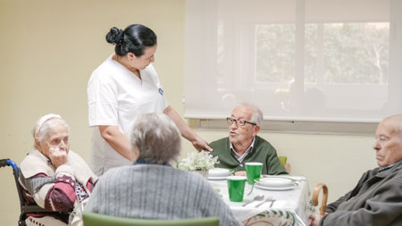 Caregiver talking to senior man in canteen at nursing homeの写真素材