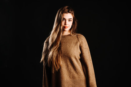 Beautiful female model standing against black backgroundの写真素材