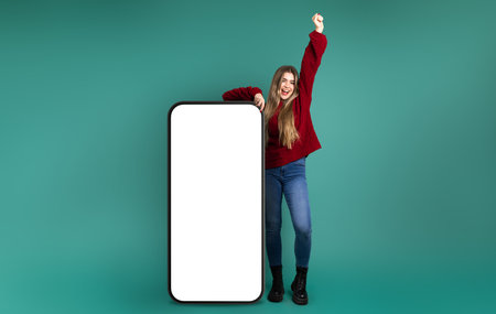 Model woman with animated pose celebrating happily , leaning on a giant cellの写真素材