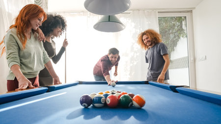 Happy man playing pool with friends in bright game room at home