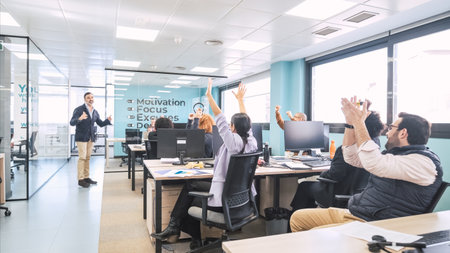 Businesspeople applauding as manager shares good news with them in officeの写真素材