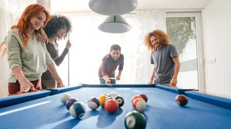 Cheerful multiethnic friends playing pool together at homeの写真素材