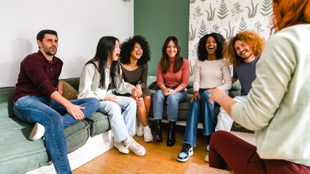 Cheerful diverse friends enjoying leisure time in living room at homeの写真素材