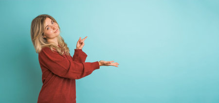 Happy young woman showing mockup space in blue studio