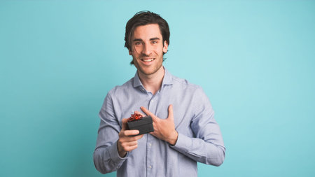 Happy adult man receiving gift box in blue studio