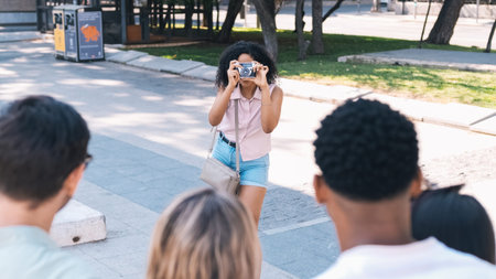 Woman photographing friends with digital camera on city street