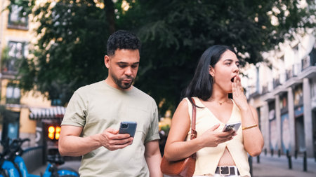 Bored couple using mobile phones on city streetの写真素材