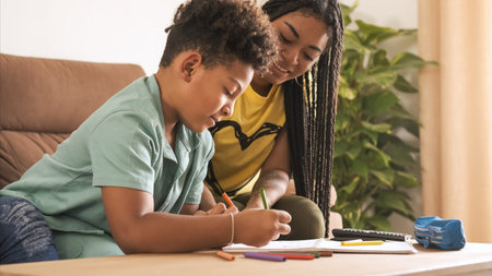 Young woman coloring with little brother in living room at home