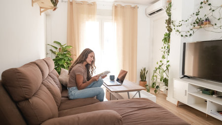 Serious woman reading diary in living room at homeの写真素材