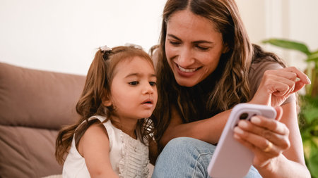 Happy mother and daughter using smartphone at home